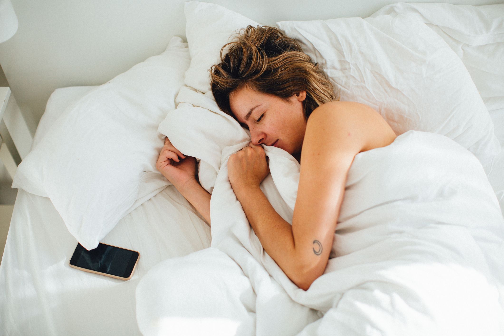 Mulher dormindo com iPhone na cama monitorando o sono