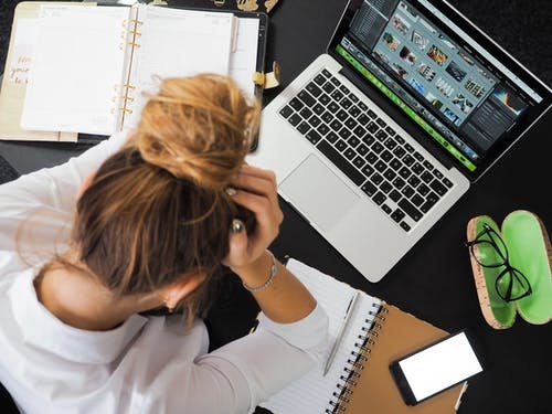 Mulher com as mãos na cabeça em frente a um macbook